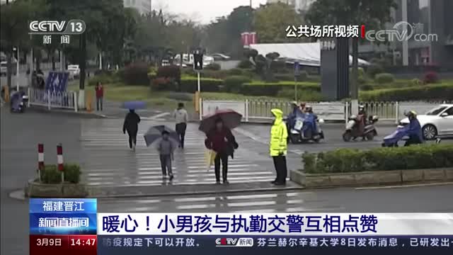 暖心一幕！男孩踮脚为交警撑伞